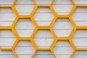 Étagère en bois à motif nid d'abeille jaune sur un mur en planche de bois peint en blanc photo