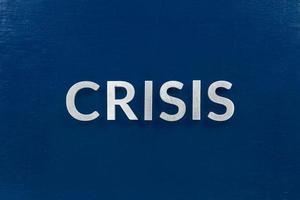 le mot crise posé avec des lettres en métal argenté sur la surface bleue pour le fond du marché boursier photo