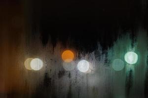 texture de verre de fenêtre de nuit brumeuse sale avec des réverbères flous en arrière-plan photo