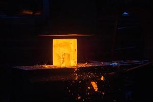 photo en gros plan du processus de forgeage manuel de l'acier chaud avec une grande machine à marteaux mécaniques