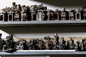 Vieilles pièces de moteur en métal sale sur une étagère de garage sombre photo