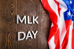 le mot mlk day posé avec des lettres en métal argenté sur une surface en bois avec un drapeau américain froissé sur le côté droit photo