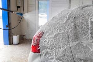 processus d'application de mousse de savon détergent pendant le lavage à l'intérieur à la station de lavage de voiture en libre-service photo