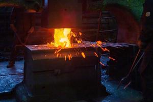 photo en gros plan du processus de forgeage manuel de l'acier chaud avec une grande machine à marteaux mécaniques