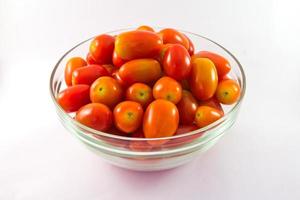 tomates bébé dans un bol en verre sur fond blanc photo