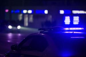 voiture de police bleue lumière la nuit en ville avec mise au point sélective et bokeh sur fond noir photo