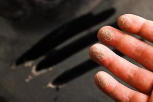 main caucasienne avec de la poussière sur le bout des doigts après avoir touché une surface poussiéreuse noire photo