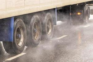 Camion-remorque à fourgon sec se déplaçant sur une route mouillée avec des éclaboussures pendant la journée photo