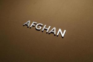 le mot afghan posé avec des lettres en métal argenté sur un tissu en toile kaki beige rugueux photo