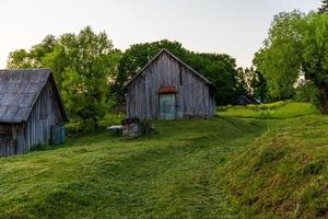 Anciennes granges en bois sur cour avec pelouse tondue au soir d'été photo
