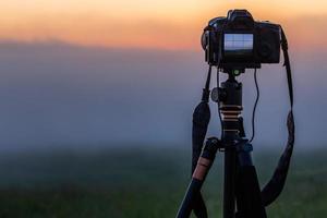 appareil photo numérique noir sur trépied prise de vue paysage brumeux du matin à l'été avec mise au point sélective