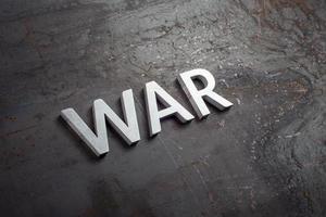 Le mot guerre posé avec des lettres en métal argenté sur une surface en acier brut nu noir dans une perspective diagonale à lattes photo