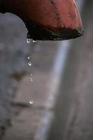 des gouttelettes d'eau s'écoulent d'un vieux tuyau rouillé. pénurie d'eau sur la planète. concept de problème de pollution des terres et de sources fossiles. photo