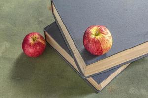 pomme sur la pile de livre sur l'étude de table en bois vert. photo