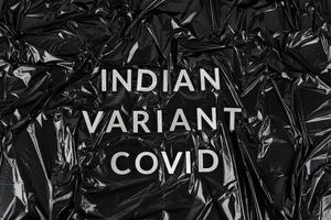 mots variante indienne covid posé avec des lettres en métal argenté sur fond de sac en plastique noir froissé photo