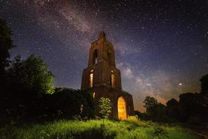 ruine du clocher de nuit dans la forêt la nuit étoilée avec lumière interne photo