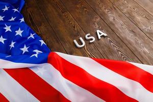 Le mot usa posé avec des lettres en métal argenté sur la surface de la planche de bois avec le drapeau froissé des États-Unis d'Amérique photo