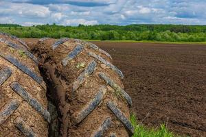 Roues doubles sales du tracteur agricole aux beaux jours d'été avec champ labouré en arrière-plan photo