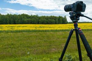 appareil photo sans miroir professionnel moderne sur trépied tirant champ jaune sur trépied, gros plan