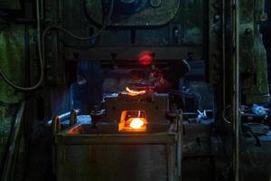 pièces en acier chaud forgées fraîches après formage à la presse dans une usine sombre et sale photo