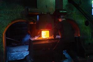 image en gros plan du processus de forgeage sans acier chaud avec une grande machine à marteaux mécaniques photo