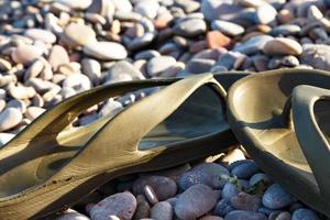 tongs vertes sur une plage de pierres. image horizontale. photo