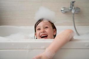 petite fille dans le bain jouant avec de la mousse photo