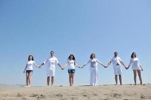 groupe de personnes heureuses s'amuser et courir sur la plage photo