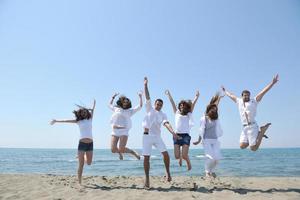 groupe de personnes heureuses s'amuser et courir sur la plage photo