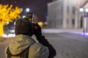 photographe professionnel tirant vue sur l'architecture de nuit à l'hiver enneigé photo