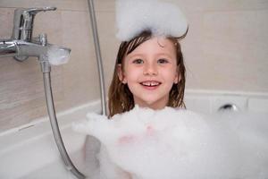 petite fille dans le bain jouant avec de la mousse photo