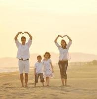 jeune famille heureuse s'amuser sur la plage au coucher du soleil photo