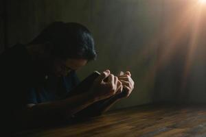 main de personne de prière sur fond noir. une femme catholique chrétienne prie Dieu dans le noir à l'église. fille croit et foi en jésus christ. la religion du christ et le christianisme adorent ou prient le concept. photo