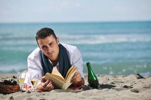 homme lisant un livre à la plage photo