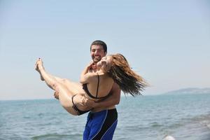 heureux jeune couple s'amuser sur la plage photo