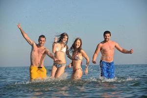 groupe de personnes heureuses s'amuser et courir sur la plage photo