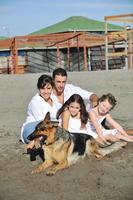 famille heureuse jouant avec un chien sur la plage photo