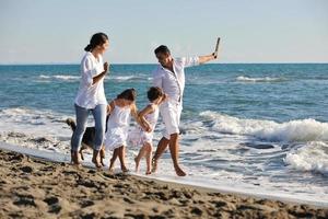 famille heureuse jouant avec un chien sur la plage photo