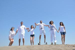 groupe de personnes heureuses s'amuser et courir sur la plage photo