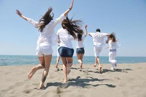 groupe de personnes heureuses s'amuser et courir sur la plage photo