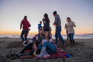 couple profitant avec des amis au coucher du soleil sur la plage photo