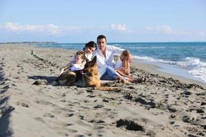 famille heureuse jouant avec un chien sur la plage photo