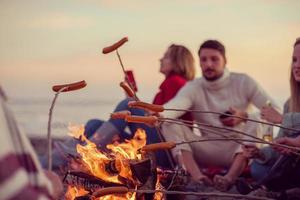 groupe de jeunes amis assis près du feu à la plage photo