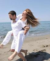 heureux jeune couple s'amuser sur la plage photo