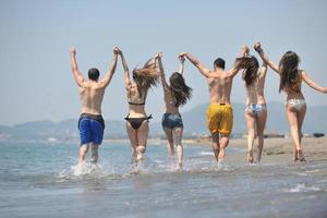 groupe de personnes heureuses s'amuser et courir sur la plage photo