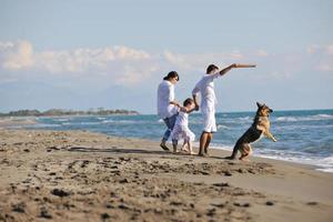 famille heureuse jouant avec un chien sur la plage photo