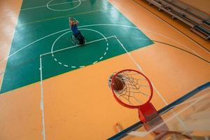 Voir la photo d'un vétéran de la guerre jouant au basket-ball dans une arène sportive moderne. le concept de sport pour les personnes handicapées