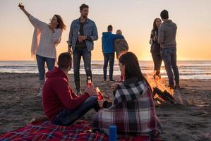 couple profitant avec des amis au coucher du soleil sur la plage photo