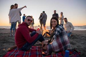 couple profitant avec des amis au coucher du soleil sur la plage photo