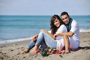 jeune couple profitant d'un pique-nique sur la plage photo